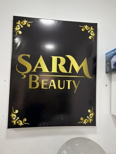 Digər salon, tibbi mebel: Qara fonda qızılı rəngdə “ŞARM Beauty” yazısı olan reklam lövhəsi