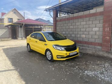 ролик для авто: Яркий желтый седан Kia Rio, припаркованный у кирпичной стены и забора