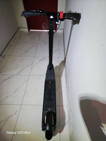 skuter oturacaglı: Qara rəngdə olan elektrik skuter. İdarəetmə paneli skuterin