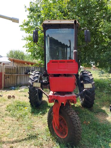 tekərlər: Kənd təsərrüfatı işləri üçün istifadə olunan qırmızı rəngli traktor
