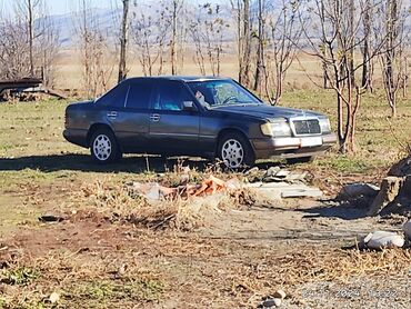 домкрат для машины: Седан Mercedes-Benz W124 в темном цвете кузова. Автомобиль оснащен