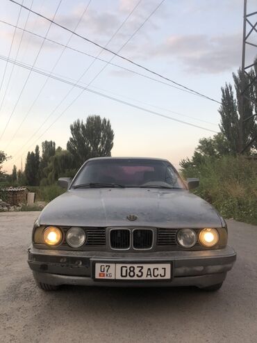 арзан машина мерс: Седан BMW 5 серии (E34) серого цвета, оборудованный передними фарами с