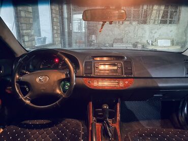 срочно продам авто в связи с переездом: Седан Toyota Camry темного цвета, оснащенный стандартными