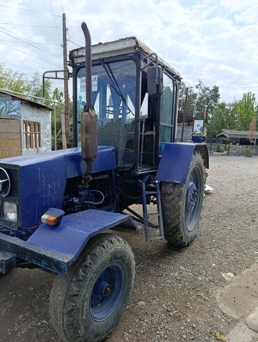qosqular: Mavi rəngli təkərli traktor, qabaqdan egzoz borulu və kabinli model