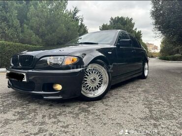 BMW: Qara rəngdə olan BMW E46 sedanı. Avtomobilin ön hissəsində duman