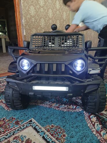 Uşaq üçün elektrik maşınları: Qara rəngdə olan uşaq elektrik avtomobili. Böyük təkərləri və ön