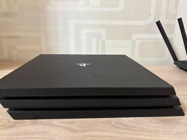 PS4 (Sony Playstation 4): Qara rəngdə olan PlayStation 4 Pro oyun konsolu. Cihaz evdə əyləncə