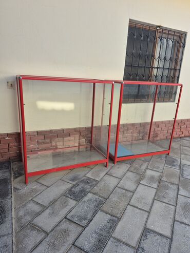 Şüşə yan divarları və qırmızı metal çərçivəsi olan bu vitrin