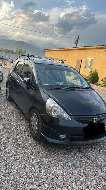 маленькая машина: Черный хэтчбек Honda Fit с правым рулем, оснащенный багажником на