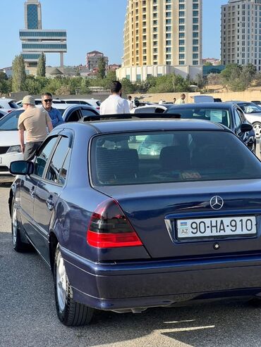Mercedes-Benz: Tünd göy rəngdə, lyuklu Mercedes-Benz sedan. Arxa tərəfdəki