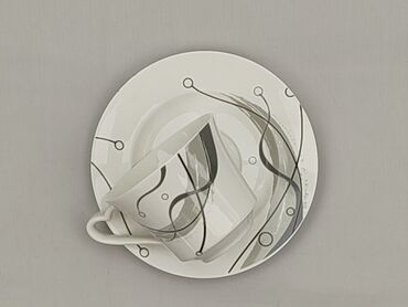 Filiżanka ze spodkiem wykonana z białej porcelany, ozdobiona