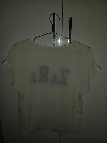 yay krasovkalari: Ağ rəngli qısaqoll bluzka. Ön hissədə iri qara “ZARA” yazısı var — 2