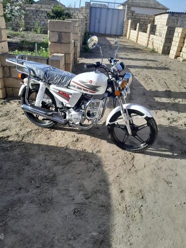 Ağ rəngli, tək oturacaqlı motosiklet. Ön və arxa hissədə baqaj daşımaq