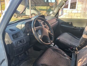 Mitsubishi: Ağ rəngli, 4 qapılı Mitsubishi Pajero SUV. Avtomobilin arxa hissəsində — 5