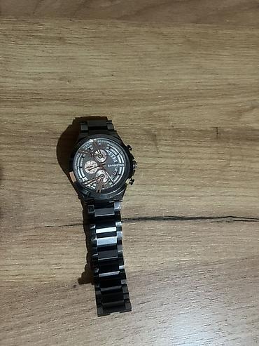 g shock kişi saatları: Qara rəngli, metal kəmərli kişi qol saatı. Saatın siferblatı — 1