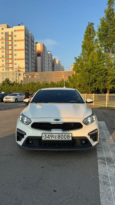 грандеур машина: Белый седан Kia K3, оснащенный черной решеткой радиатора и фарами со