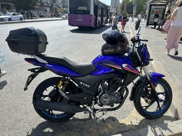 Motosiklet tünd mavi rəngdədir və arxa tərəfində əşyaları saxlamaq