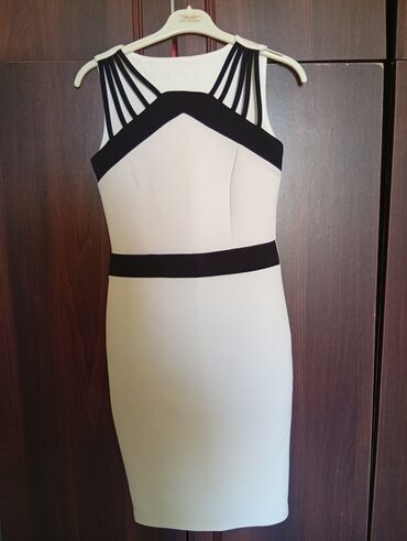 Üst geyimi: V-yaxalı və qara kəmər detallı, qolsuz bodycon mini don. Bu don ağ və