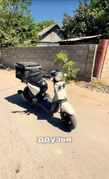 спартивный мото: Скутер белого цвета, оснащенный черным грузовым кофром. Идеально