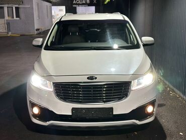 домик на колесо: Белый минивэн Kia Carnival с современным дизайном кузова. Автомобиль