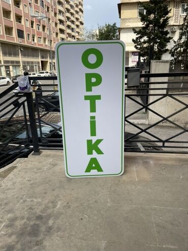 Bu, “OPTİKA” yazısı olan ağ rəngli, yaşıl haşiyəli uzunsov lövhədir