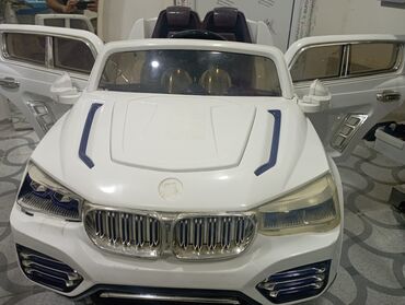 Uşaqlar üçün nəzərdə tutulmuş ağ rəngli elektrikli avtomobil. İki