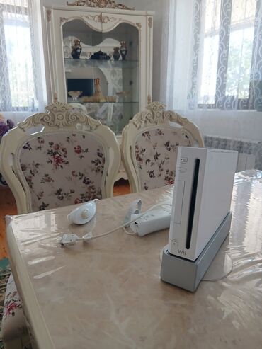 xbox 360 oyunları: Ağ rəngdə olan Nintendo Wii oyun konsolu, stendi və idarəetmə pultları
