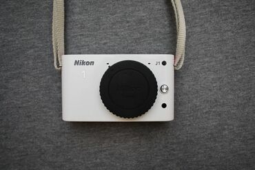 j1 mini: Nikon 1 J1 Body ağ rəngdə. Kosmetik görünüşü çox yaxşıdır. Kəmərin ağ
