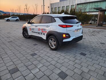 корейские автомашины: Белый кроссовер Hyundai Kona с черными элементами кузова и