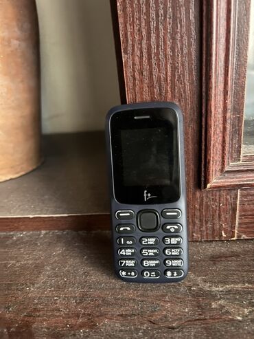 F+ markalı, tünd boz rəngli, düyməli mobil telefon. Qara rəngli