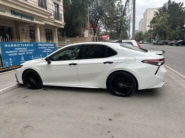 дополнительная фара: Белый седан Toyota Camry с четырехдверным кузовом, припаркованный на