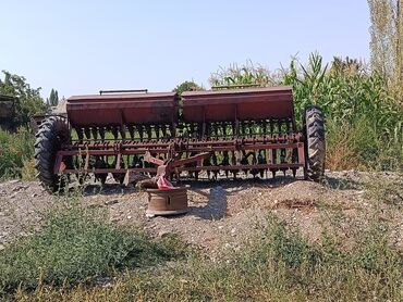 Механическая зерновая сеялка красного цвета, предназначенная для