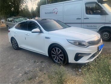 машина кейж: Белый седан Kia K5, отличающийся современным дизайном кузова. Модель