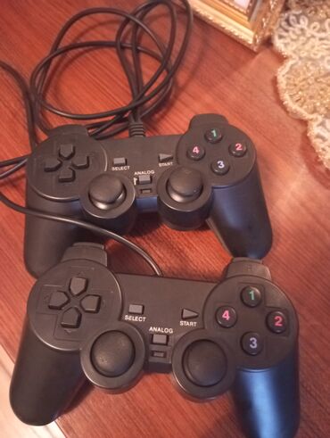 Naqilli qoşulma ilə iki ədəd qara rəngli gamepad. Hər birində