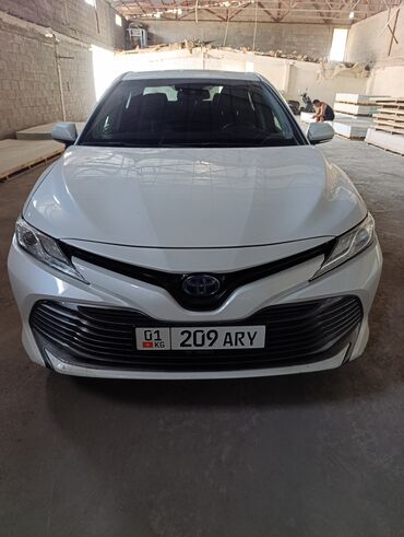 тайота камри 2021: Белый седан Toyota Camry с гибридной силовой установкой. Автомобиль