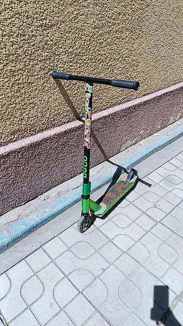 Трюковой самокат в черно-зеленом цвете. Подходит для катания по