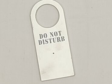 Biała zawieszka na klamkę z napisem "DO NOT DISTURB". Jest to prosty i