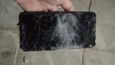 Ekranı sınmış vəziyyətdə olan qara rəngli smartfon. Cihazın ekranında