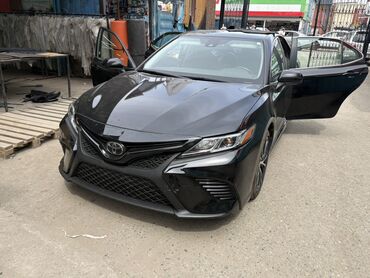 машина семейная: Чёрный седан Toyota Camry. Автомобиль имеет элегантный внешний вид и