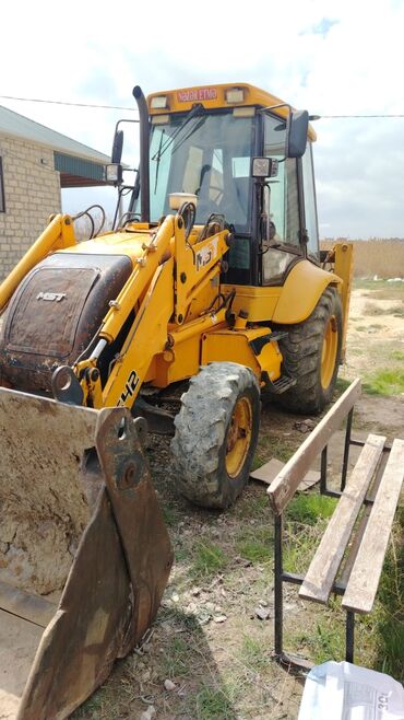 Traktor qoşquları: MST M542 modelinin sarı rəngli ekskavator yükləyicisi, ön hissədə