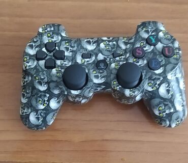 pileteler: PlayStation 3 üçün qara rəngli, kəllə naxışlı oyun konsolu. İki analoq