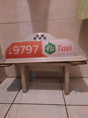 Колпак такси с надписью "Bi Taxi" и номером телефона 9797. На задней
