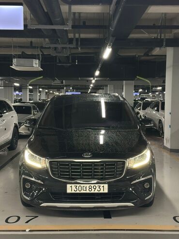 машина кейж: Черный минивэн Kia Carnival, припаркованный в подземном гараже. Модель