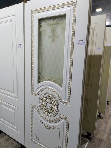 Məhəccərlər: Ağ rəngdə, zərif qızılı naxışlarla bəzədilmiş qapı. Qapının yuxarı