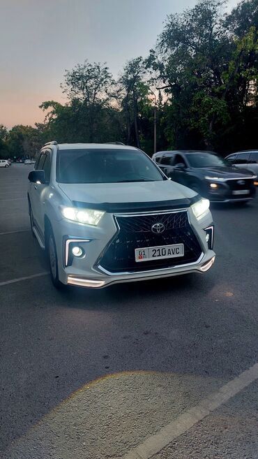 семиместные машины: Белый внедорожник Toyota Highlander. Автомобиль оснащен боковыми