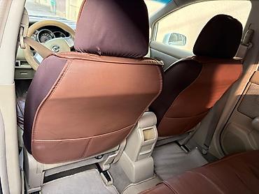 nisan note: Ağ rəngli Nissan Tiida sedan. Avtomobilin salonu açıq bej tonlarda — 2