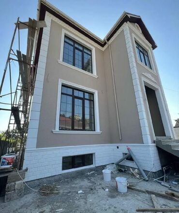 qapi dekoru: İki mərtəbəli, bej rəngli, müasir üslubda inşa edilmiş ev. Evin fasadı