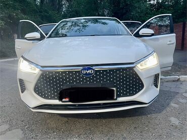 электромобиль byd e5: Белый электромобиль BYD с открытыми передними дверями. Автомобиль