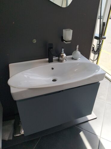 Hamam üçün aksessuarlar: Ağ rəngli, oval formalı keramika lavabo, boz rəngli dolabın üstündə