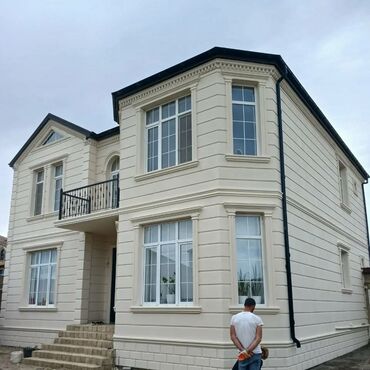 dam örtükleri: İki mərtəbəli, açıq rəngli fasadı olan fərdi yaşayış evi. Pəncərələr